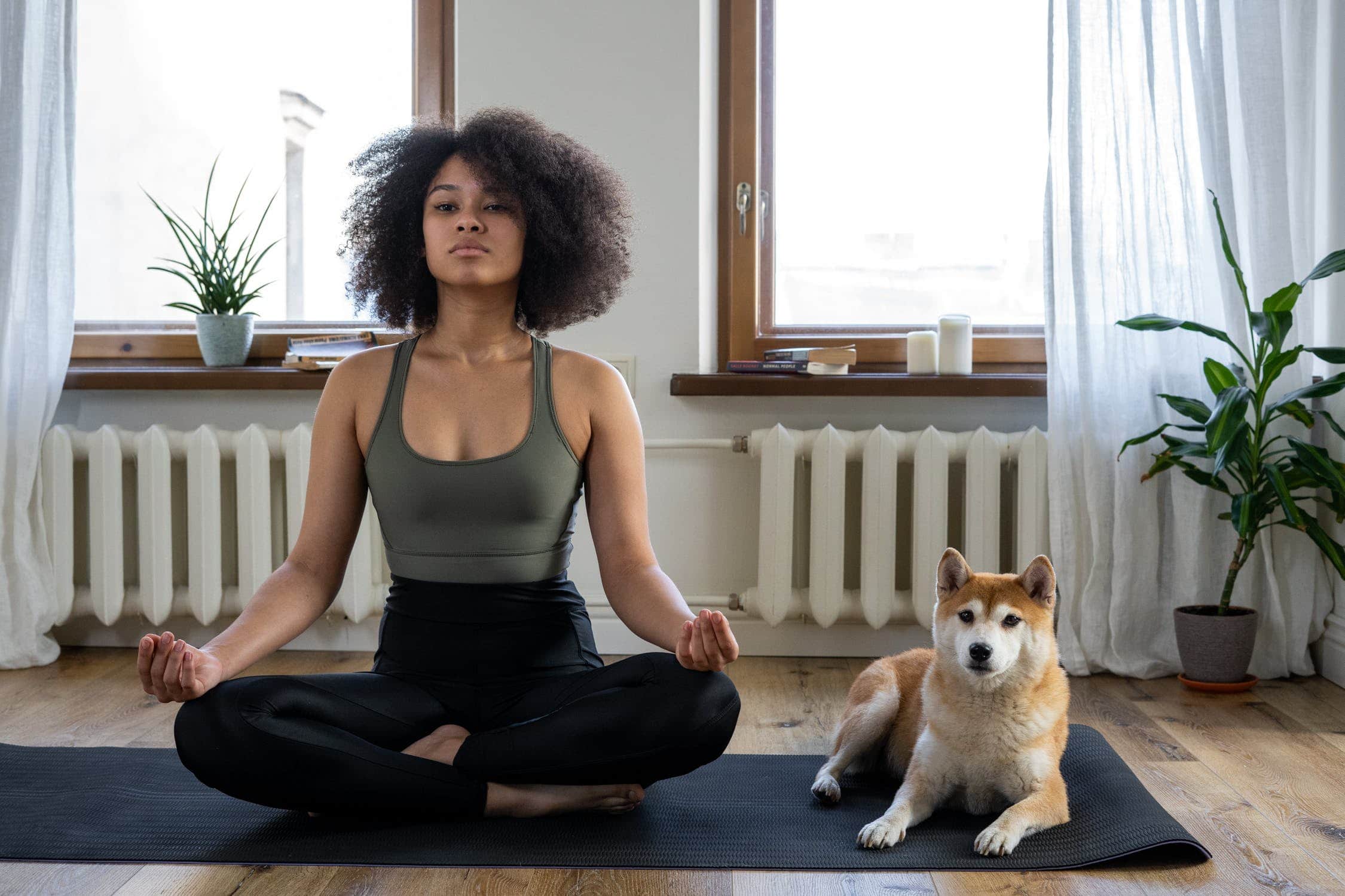 Young woman in a grounding yoga pose next to a dog