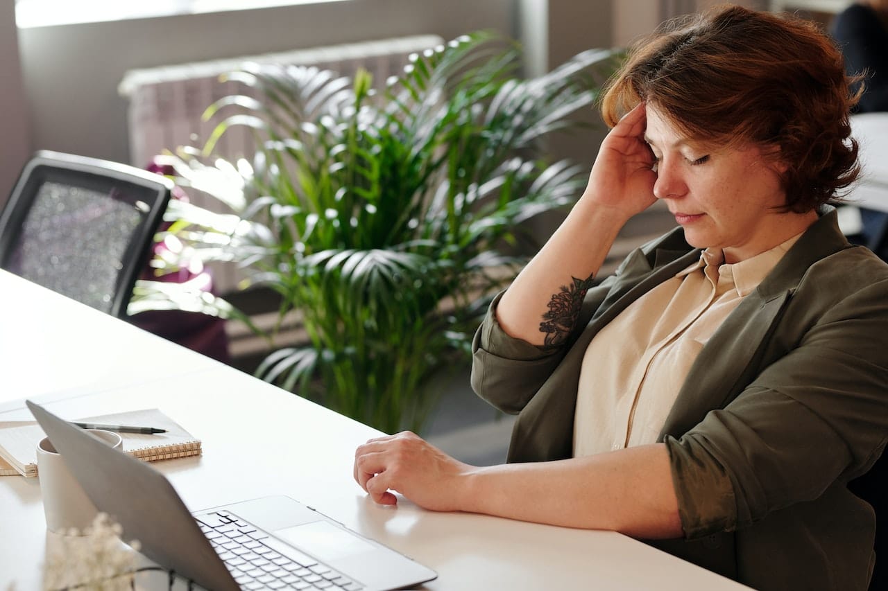Woman working with a headache is an example of presenteeism